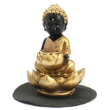 Statue of a Buddha figure on a lotus flower with gold and black colors on a white background